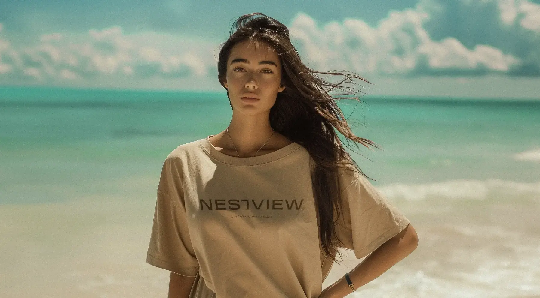 Nestview’s identity applied to a shirt in a sunlit coastal setting